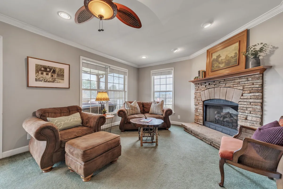 A close-up view of a plush sofa arranged by a glowing fireplace, with tasteful mountain-inspired décor, a decorative lamp, and wall art enhancing the cozy atmosphere. The setting invites relaxation and socializing in a warm, intimate space.