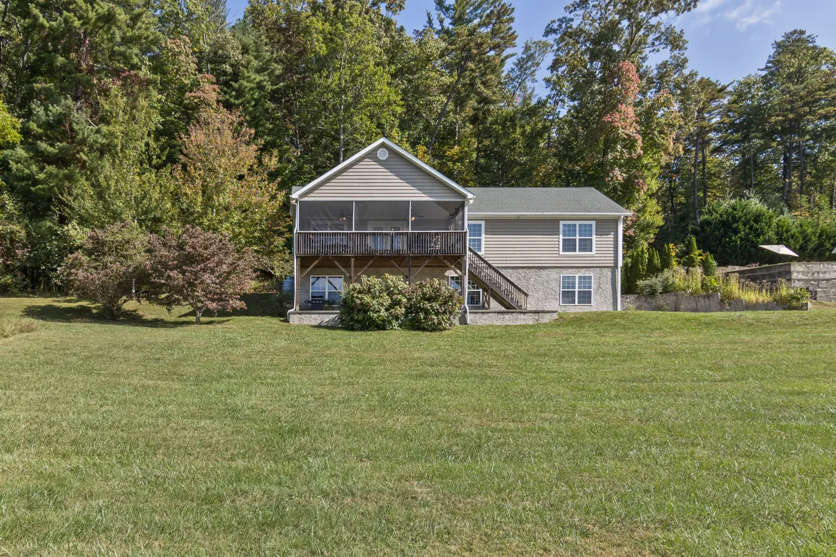 This exterior shot features the house with a large green yard and mature trees, suggesting ample outdoor space for children to play and families to gather. The welcoming, peaceful atmosphere hints at sunset views and outdoor activities.